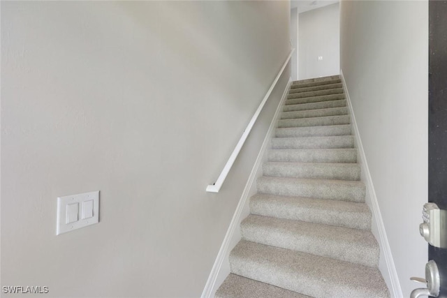 staircase featuring carpet and baseboards