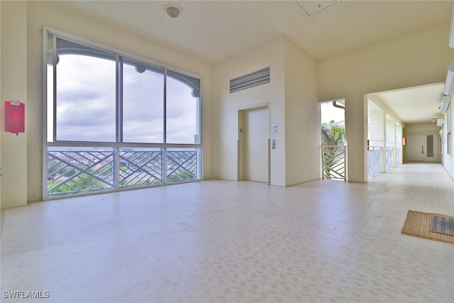 spare room featuring elevator and plenty of natural light