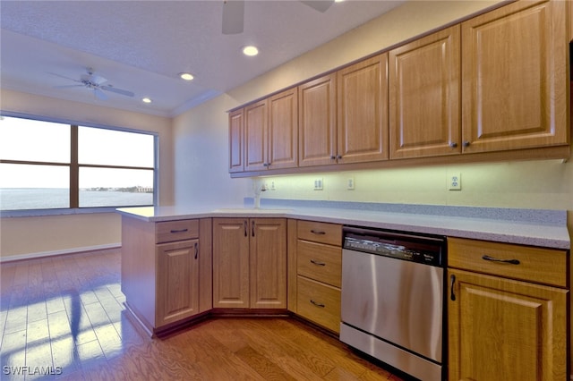 kitchen with a water view, stainless steel dishwasher, kitchen peninsula, ceiling fan, and light hardwood / wood-style flooring