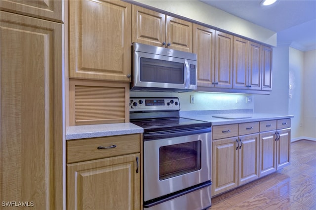 kitchen with ornamental molding, light wood-type flooring, stainless steel appliances, and light brown cabinets