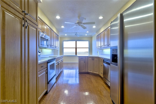 kitchen with light hardwood / wood-style floors, ceiling fan, a textured ceiling, and appliances with stainless steel finishes