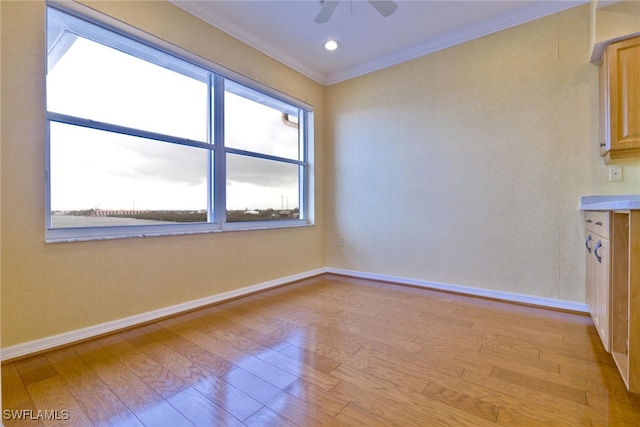 empty room with ornamental molding, a wealth of natural light, and light hardwood / wood-style flooring