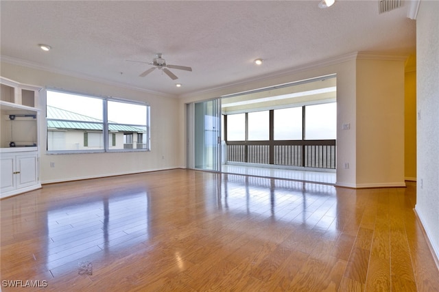 unfurnished living room with ceiling fan, a textured ceiling, light wood-type flooring, and ornamental molding