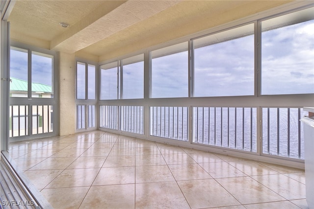 unfurnished sunroom featuring a water view and plenty of natural light