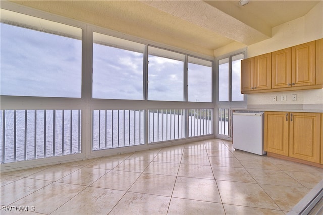 kitchen featuring dishwasher, a water view, a textured ceiling, and light tile patterned floors