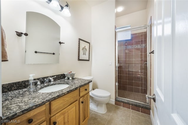 bathroom with vanity, a shower with shower door, tile patterned floors, and toilet