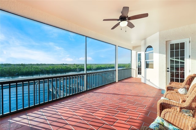 unfurnished sunroom with a water view and ceiling fan