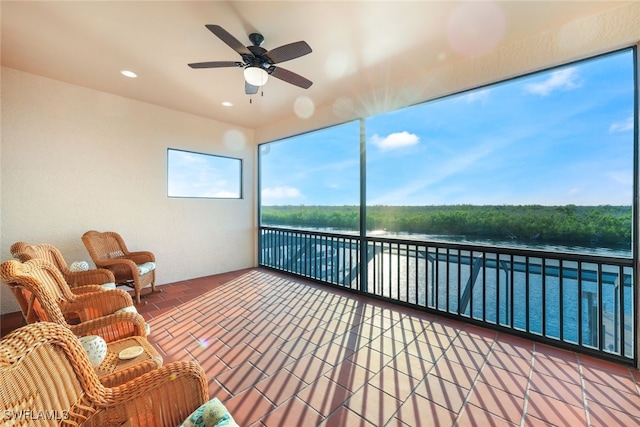 unfurnished sunroom with ceiling fan and a water view