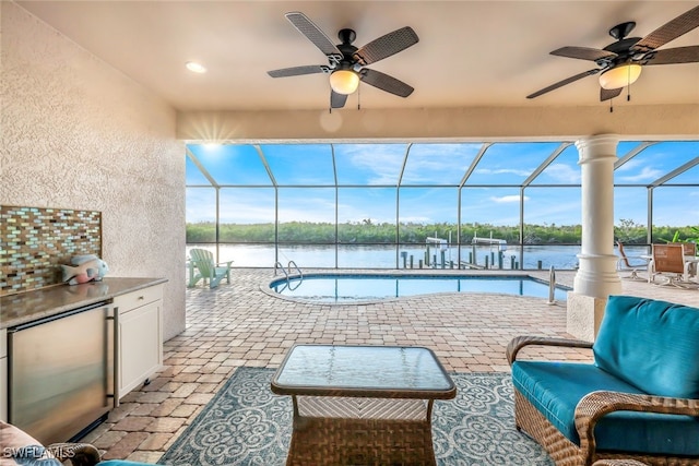 view of swimming pool featuring ceiling fan, a lanai, and a water view