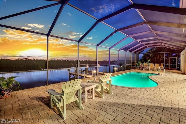 pool at dusk with a water view, glass enclosure, and a patio