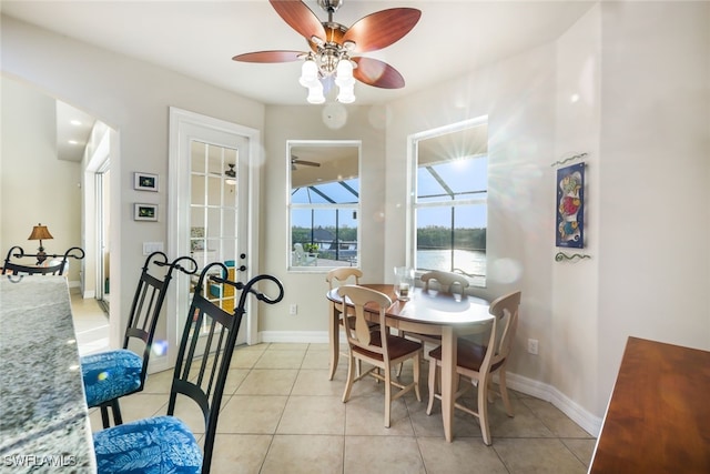 tiled dining space featuring ceiling fan and a water view