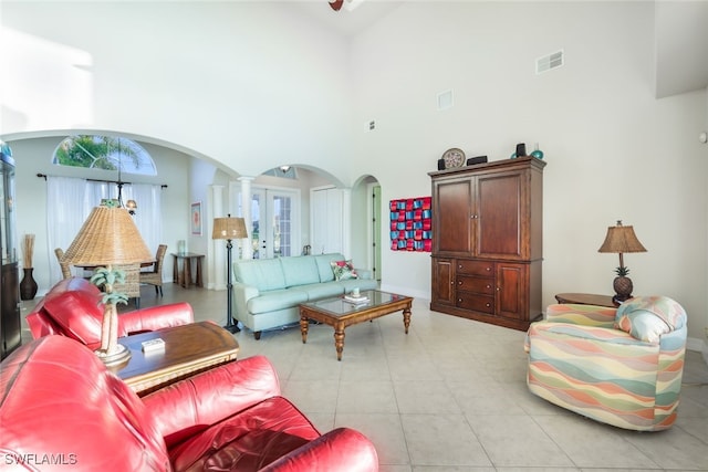 living room with light tile patterned flooring, a high ceiling, and decorative columns