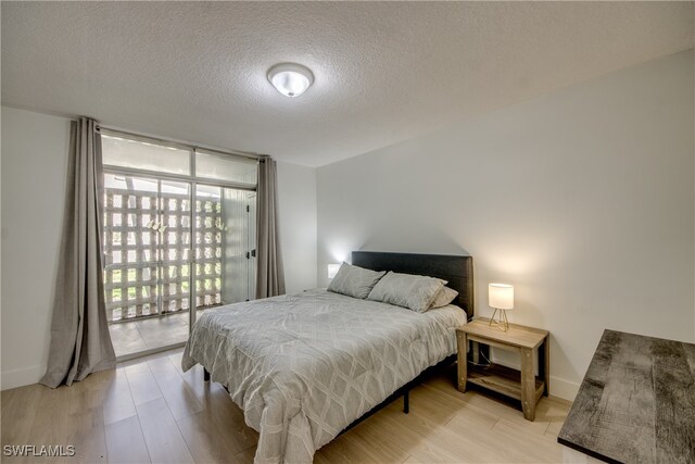 bedroom featuring light hardwood / wood-style floors, a textured ceiling, and access to outside