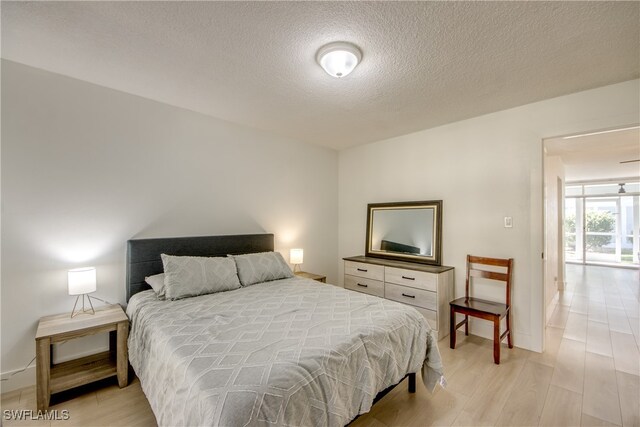 bedroom with a textured ceiling and light wood-type flooring