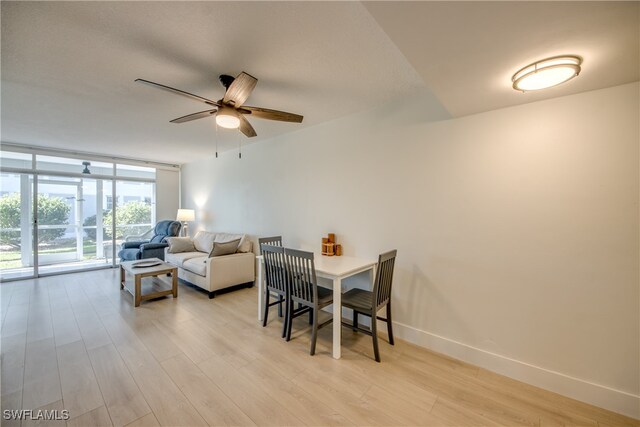 dining area featuring ceiling fan, a wall of windows, and light hardwood / wood-style flooring