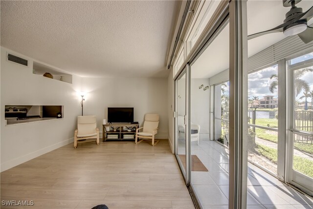 interior space with ceiling fan, plenty of natural light, a textured ceiling, and light wood-type flooring