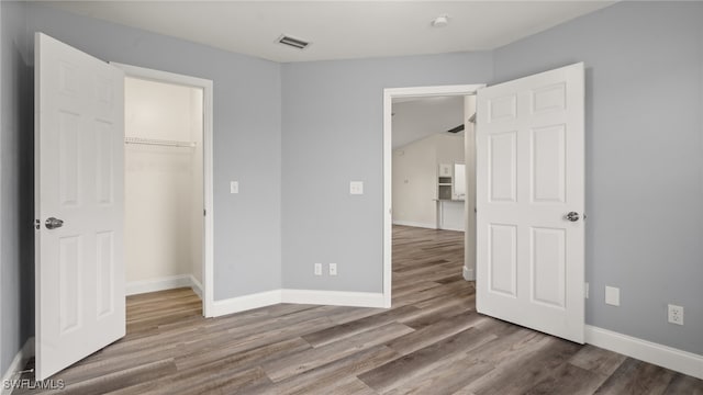 unfurnished bedroom featuring hardwood / wood-style flooring, a closet, and a walk in closet