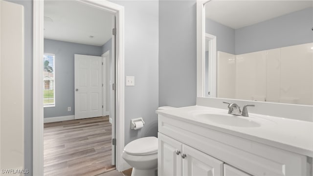 bathroom with hardwood / wood-style floors, vanity, toilet, and a shower