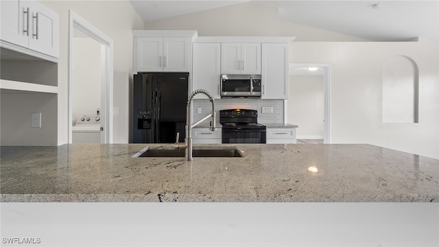 kitchen featuring black appliances, white cabinetry, lofted ceiling, and light stone counters