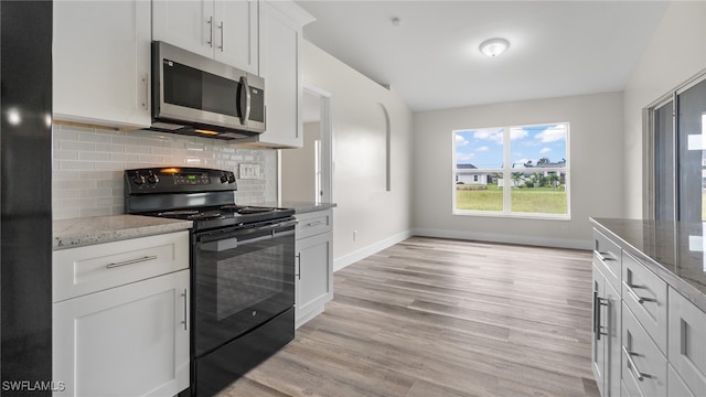 kitchen featuring light hardwood / wood-style floors, white cabinetry, black appliances, and light stone counters