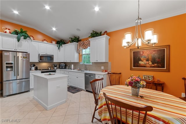 kitchen with appliances with stainless steel finishes, sink, white cabinets, lofted ceiling, and a center island