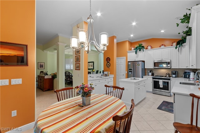 kitchen with stainless steel appliances, vaulted ceiling, white cabinets, crown molding, and decorative light fixtures