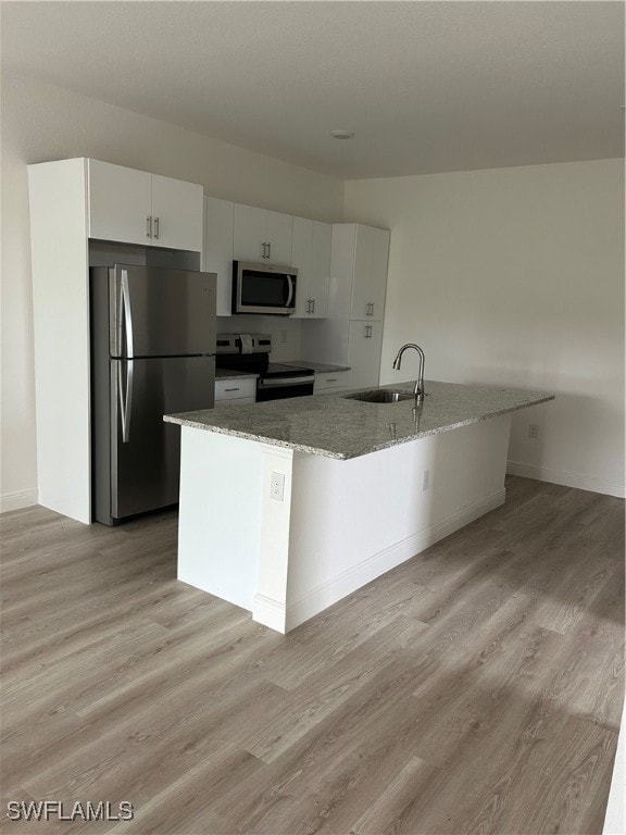 kitchen featuring white cabinets, sink, light stone countertops, light wood-type flooring, and appliances with stainless steel finishes