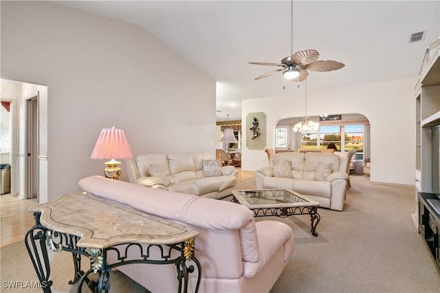 living room featuring ceiling fan with notable chandelier, light hardwood / wood-style flooring, and vaulted ceiling