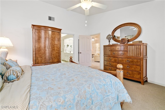 bedroom featuring ensuite bath, light carpet, and ceiling fan