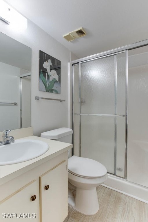 bathroom with toilet, vanity, hardwood / wood-style floors, and a shower with shower door