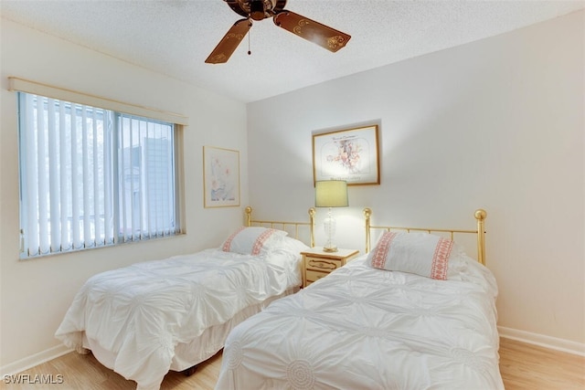 bedroom featuring light wood-type flooring, a textured ceiling, and ceiling fan