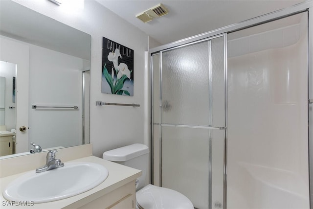 bathroom with vanity, toilet, and a shower with shower door