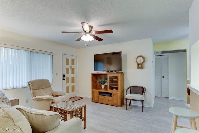 living room featuring a textured ceiling, light wood-type flooring, and ceiling fan