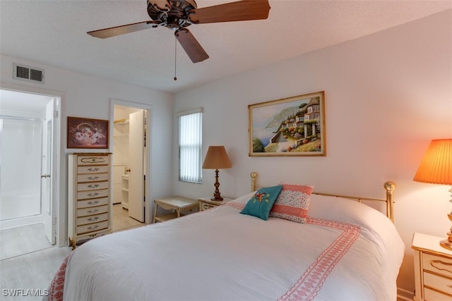 bedroom with ensuite bath, light hardwood / wood-style flooring, ceiling fan, a closet, and a spacious closet