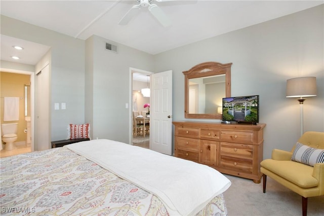 bedroom with light carpet, a ceiling fan, visible vents, and ensuite bathroom