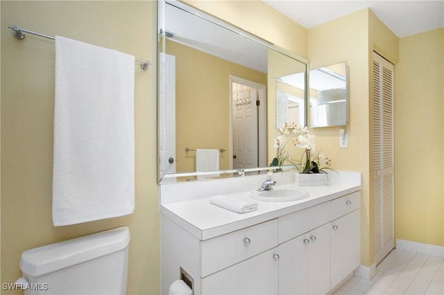 bathroom with toilet, baseboards, a closet, and vanity