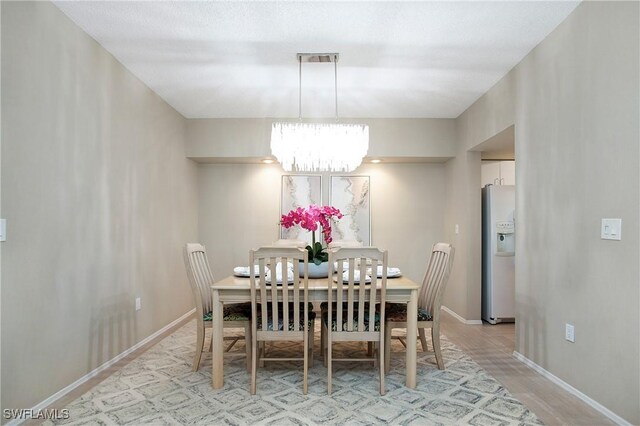 dining area with light hardwood / wood-style floors and an inviting chandelier