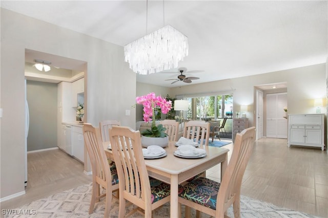 dining area featuring light wood-style flooring, baseboards, and ceiling fan with notable chandelier