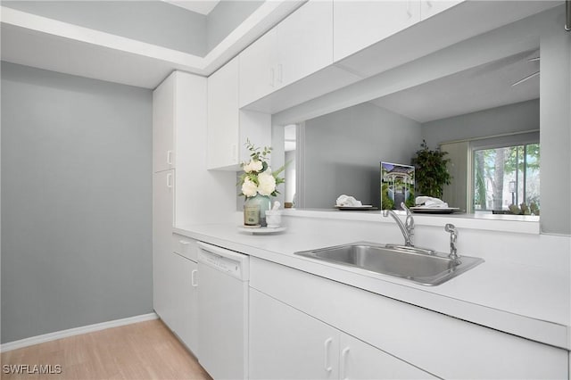 kitchen with white dishwasher, a sink, white cabinetry, light wood-style floors, and light countertops