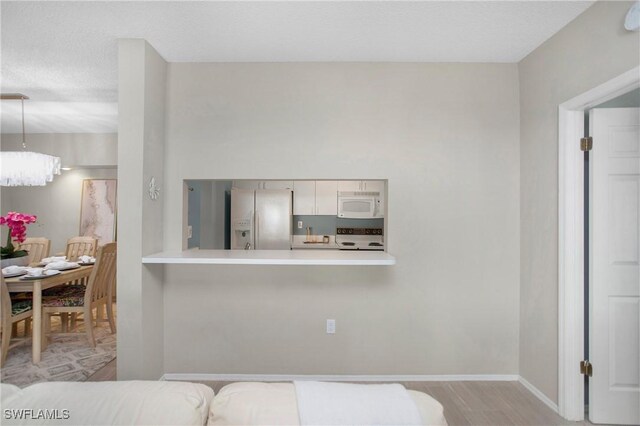 interior space featuring a chandelier, stainless steel refrigerator with ice dispenser, and light hardwood / wood-style flooring