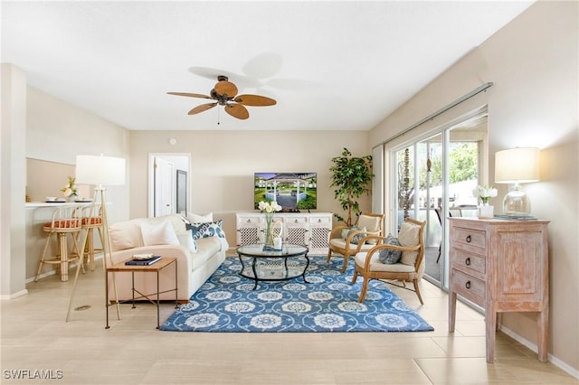 living area featuring baseboards and a ceiling fan