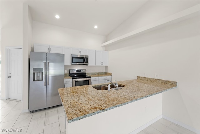 kitchen featuring stainless steel appliances, sink, kitchen peninsula, white cabinets, and vaulted ceiling