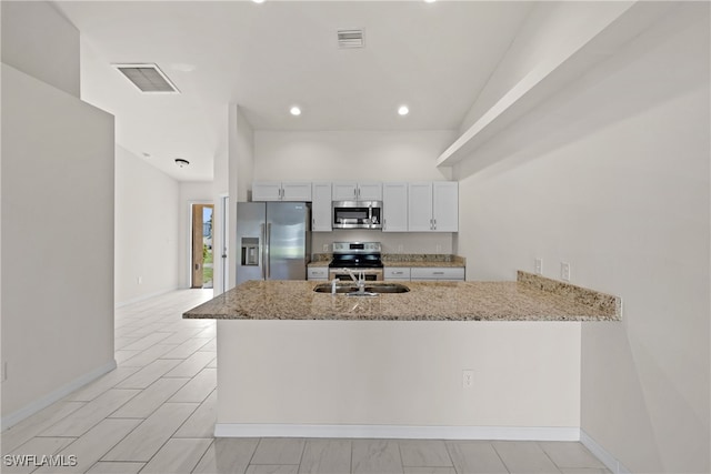 kitchen with white cabinetry, appliances with stainless steel finishes, light stone countertops, sink, and kitchen peninsula