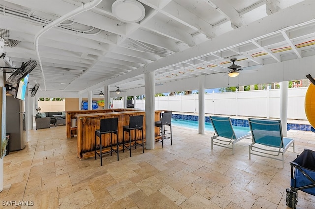 view of patio featuring a fenced in pool, ceiling fan, and an outdoor bar