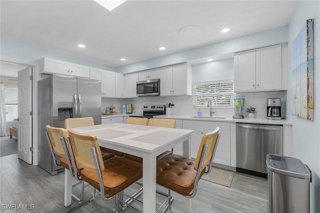 kitchen with stainless steel appliances, a wealth of natural light, white cabinets, and sink