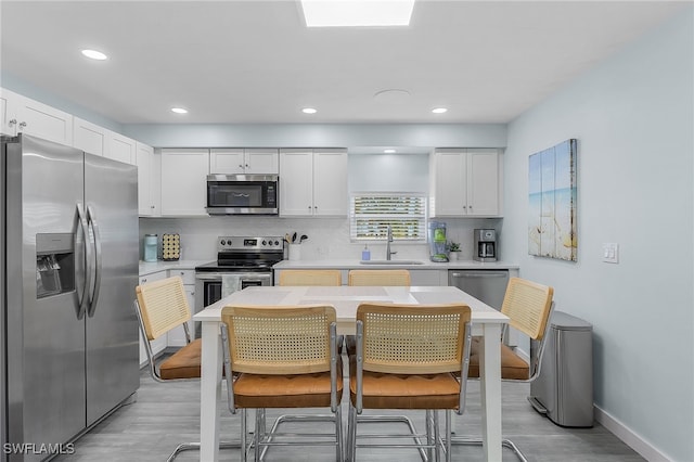 kitchen with white cabinetry, appliances with stainless steel finishes, sink, and light hardwood / wood-style flooring