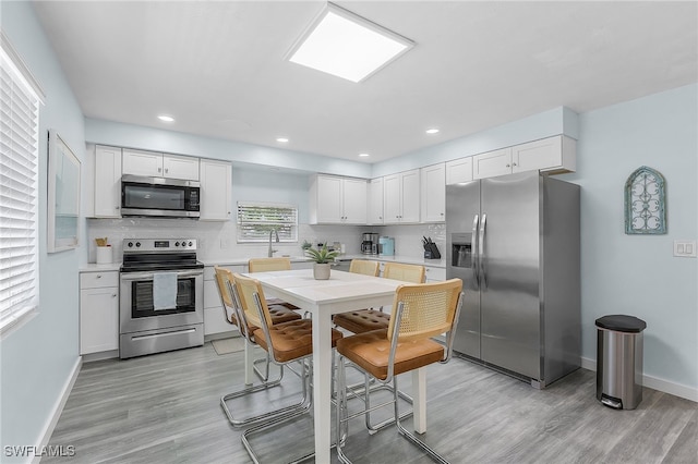 kitchen featuring white cabinets, light hardwood / wood-style floors, and appliances with stainless steel finishes