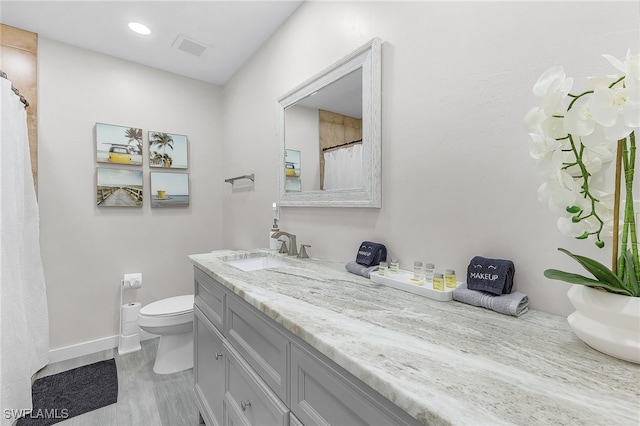 bathroom featuring wood-type flooring, vanity, and toilet