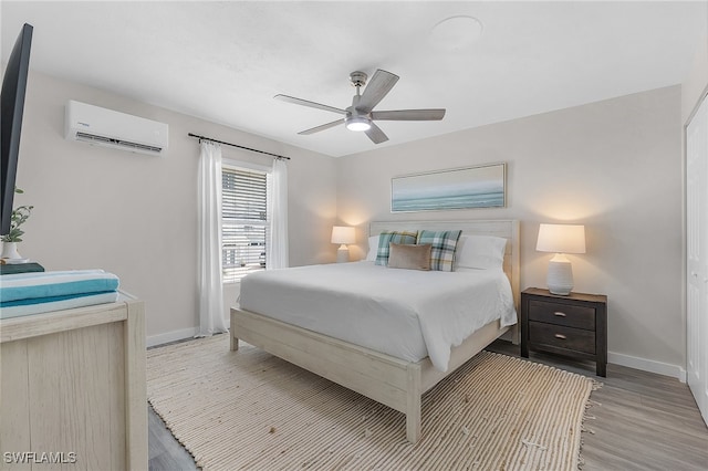 bedroom featuring an AC wall unit, ceiling fan, and light hardwood / wood-style flooring