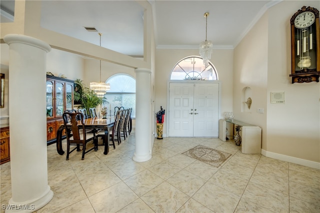 tiled foyer featuring decorative columns, a high ceiling, a chandelier, and ornamental molding